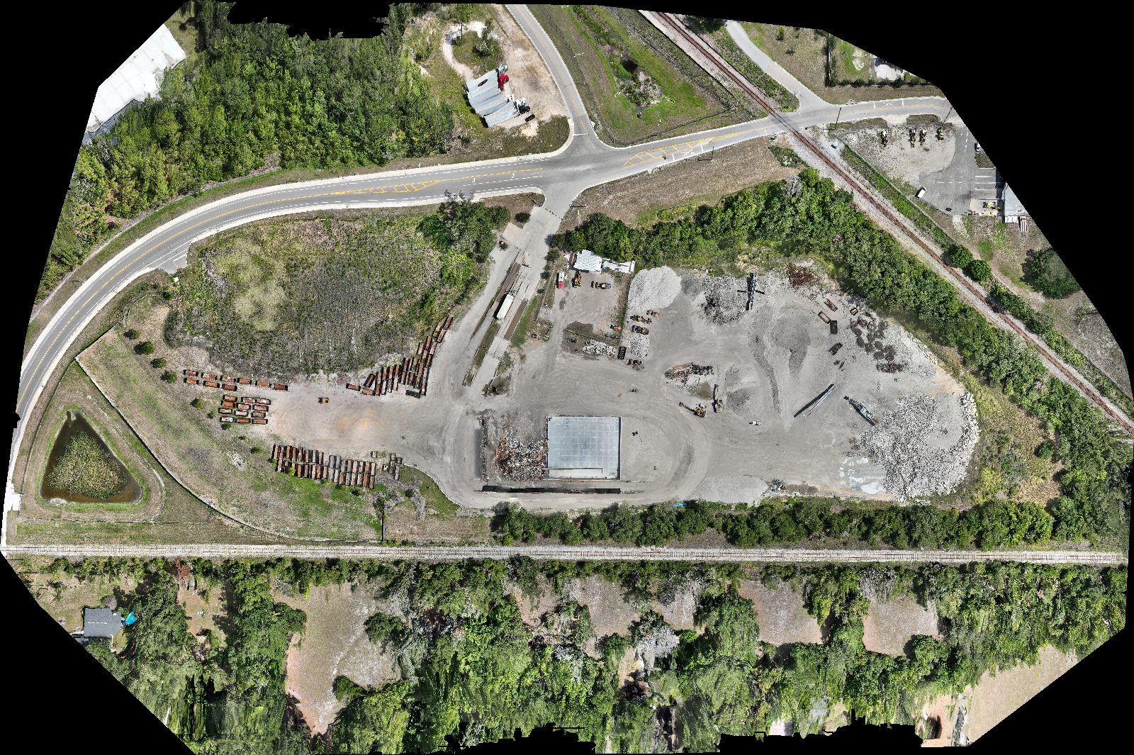 Orthomosaic of the Case Study #1 materials yard reconstructed by DroneFlow.Ai from 547 raw DJI photos: a highway junction, two rail lines, stacked culvert stock, aggregate piles, a concrete pad, active equipment and a retention pond